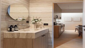 A modern bathroom with a marble vanity, a round mirror, and a vase with flowers. - Elegant apartment with AC - Le Marais (Paris)