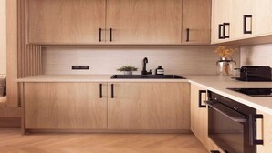 A modern kitchen with wooden cabinets, a black countertop, a sink, and an oven. - Elegant apartment - AC- 2BR-6P- le Marais (Paris)