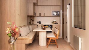 A modern kitchen with a built-in oven, microwave, and a dining area with a white table and wooden chairs. - Elegant apartment - AC- 2BR-6P- le Marais (Paris)