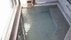 Una piscina rectangular con agua cristalina, rodeada de baldosas de piedra.