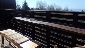 Una terraza de madera con un banco y una silla, con vistas a un paisaje pintoresco.