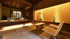 Un intérieur moderne au design minimaliste, comprenant un espace salon avec un banc et une table, un luminaire suspendu et une vue dégagée grâce à de grandes fenêtres.