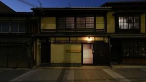 Un bâtiment traditionnel japonais, doté d’une façade en bois, d’une entrée carrelée et d’une porte coulissante.