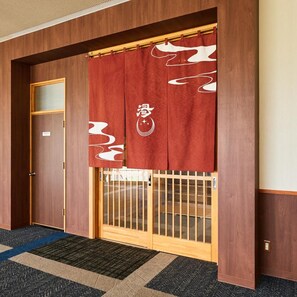A traditional Japanese interior with a wooden door, sliding glass door, and a patterned carpet. - Oe Honke (Kitami)