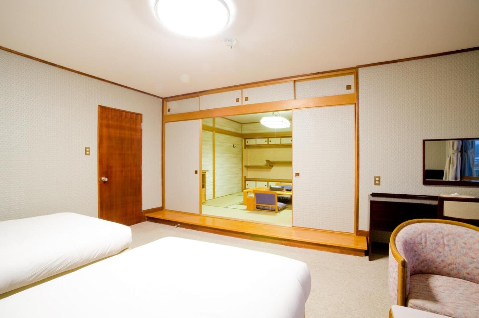 Una habitación de hotel con dos camas, un armario, un escritorio y una silla.