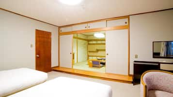 Una habitación de hotel con dos camas, un armario, un escritorio y una silla.