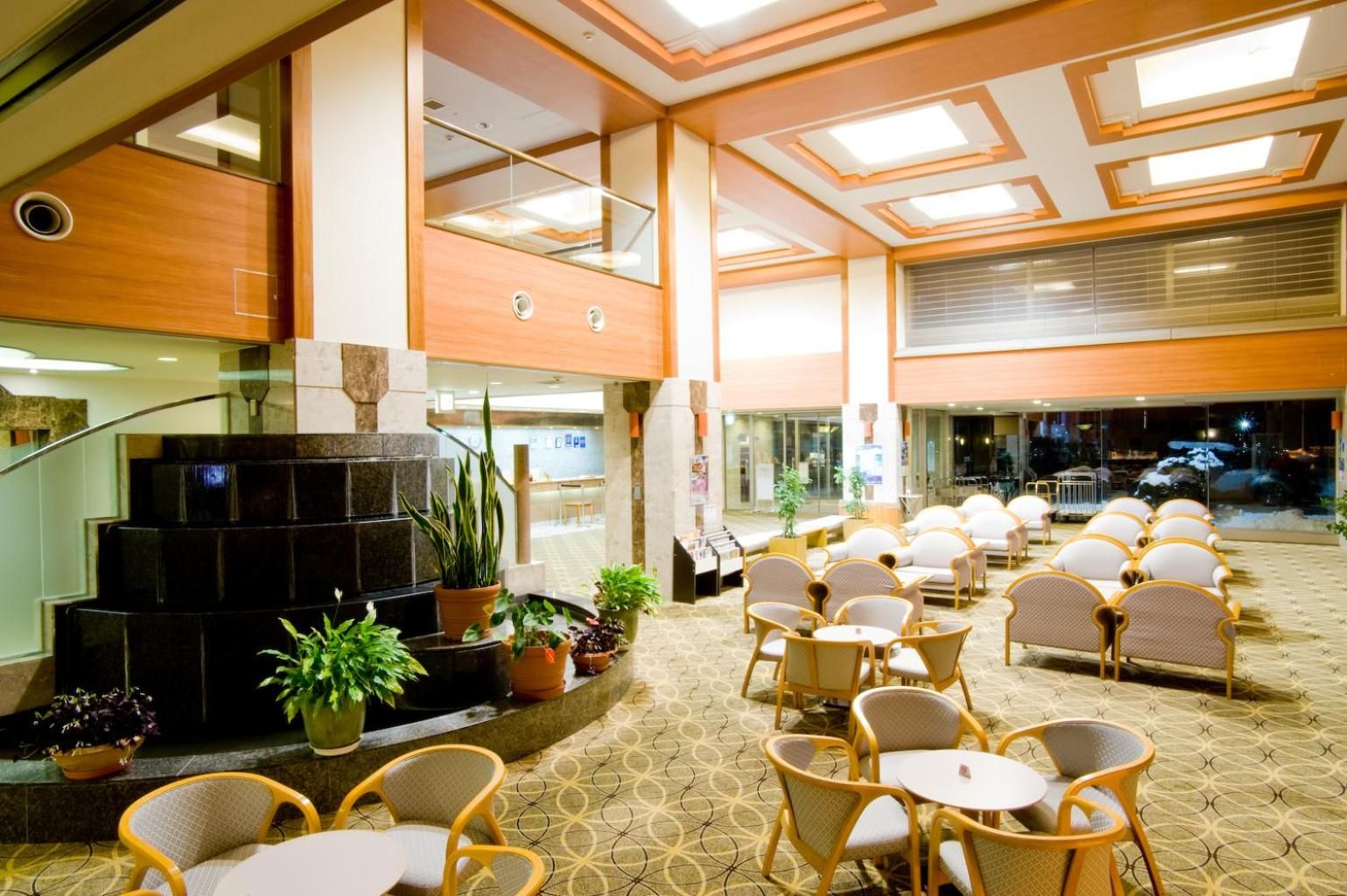 Een hotellobby met een zithoek, een trap en een receptiebalie.