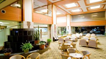 Een hotellobby met een zithoek, een trap en een receptiebalie.
