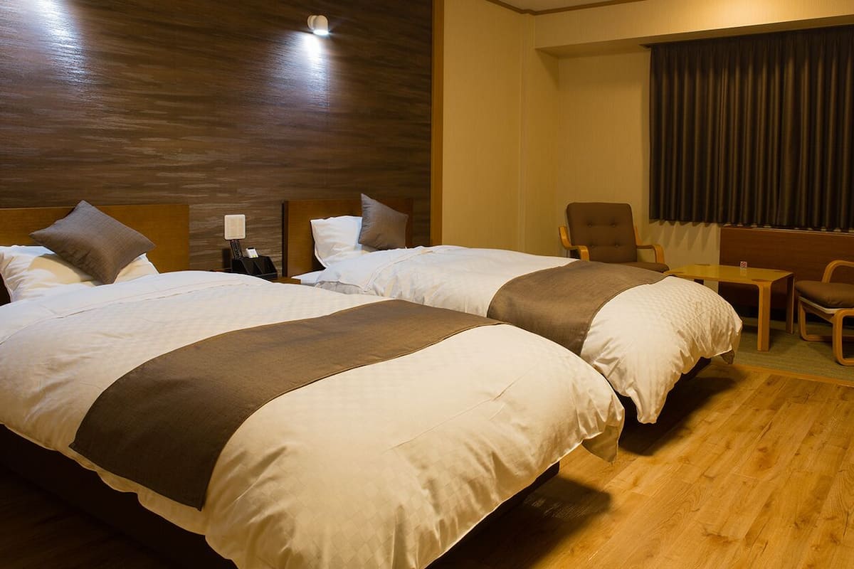 A hotel room with two beds, a desk, and a chair.