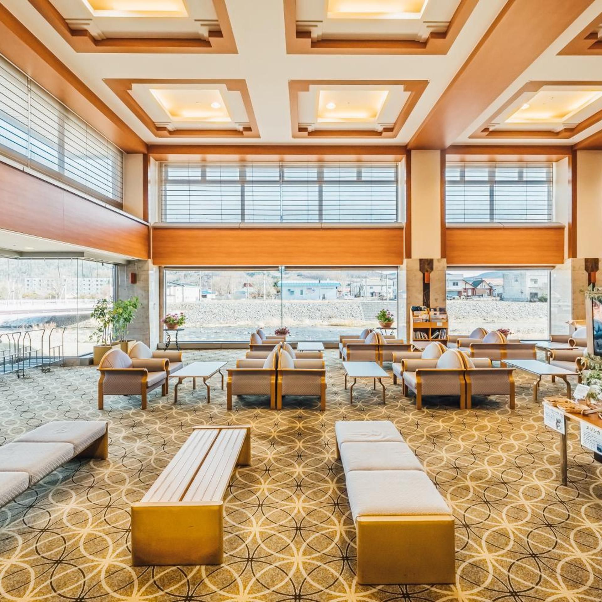 Een hotel lobby met een kamerbreed tapijt, verschillende zithoeken en grote ramen met uitzicht.