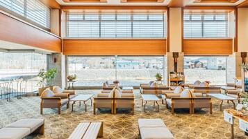 Een hotel lobby met een kamerbreed tapijt, verschillende zithoeken en grote ramen met uitzicht.