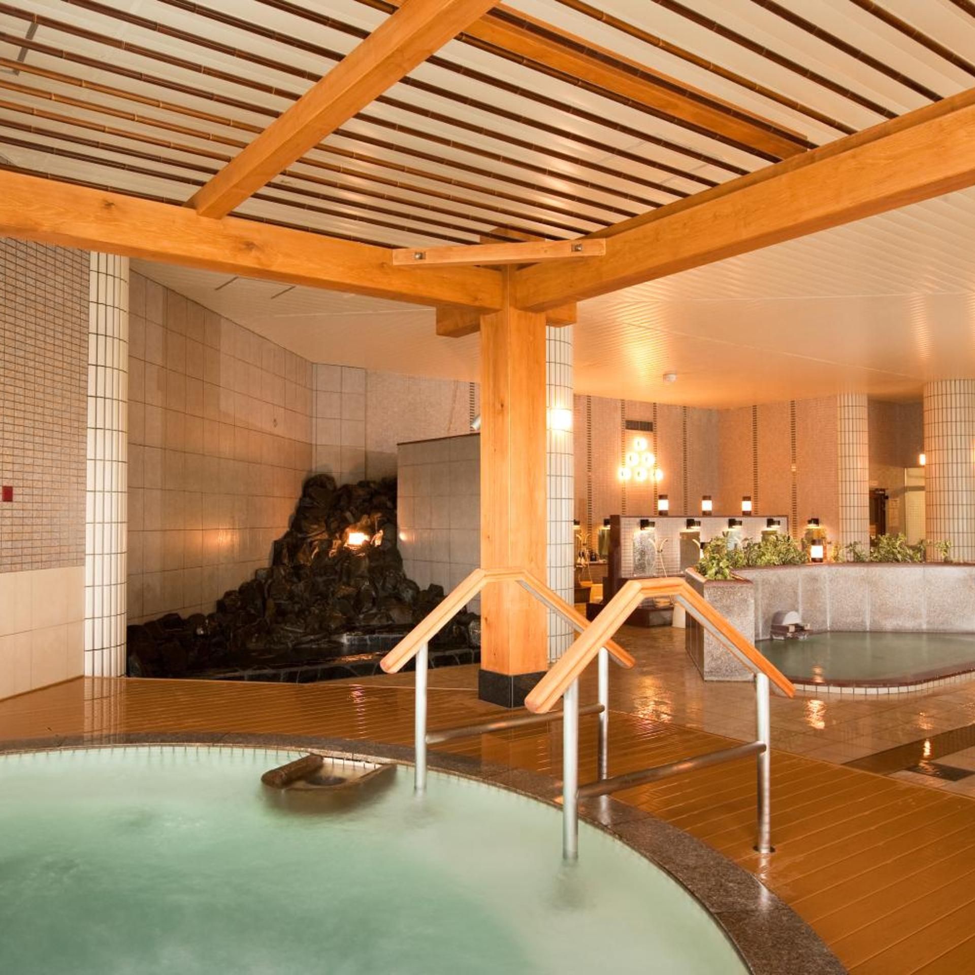 Ein Wellnessbereich mit Whirlpool, Holzbalken, gefliesten Wänden und einer Rezeption.