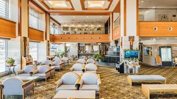 Eine Hotelhalle mit Sitzbereichen, einem Empfangstresen und Blick auf die Lobby.
