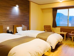 Habitación de hotel con dos camas, un escritorio, una silla y ventana con vistas.