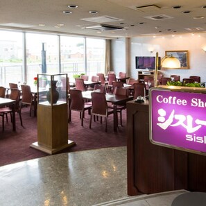 A coffee shop with tables and chairs, a reception desk, and a television screen. - Oe Honke (Kitami)