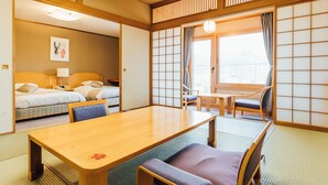 A traditional Japanese-style room with tatami flooring, a low table with cushions, a bed with a headboard, and a sliding shoji screen.