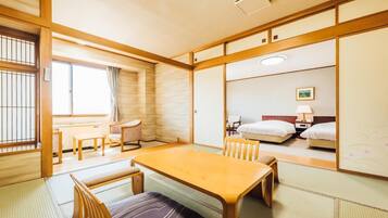 A traditional Japanese-style room with tatami flooring, a low table with chairs, a bed, and sliding doors.