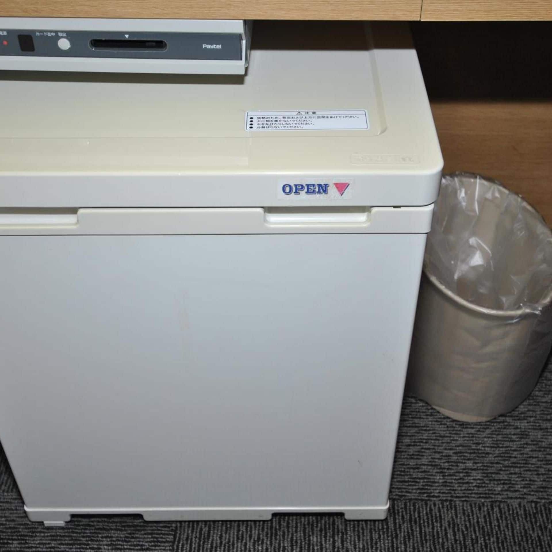 A white printer with an 'OPEN' label and a plastic bag beside it.