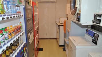 Un cuarto de lavandería con lavadora, secadora y máquinas expendedoras.