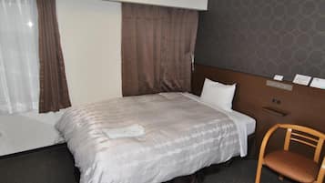 Habitación de hotel con cama, una silla de madera, una ventana con cortinas y una pared con un diseño circular.