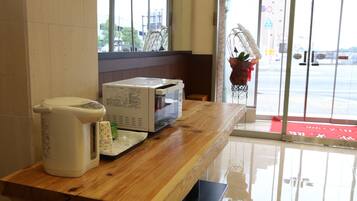 Una encimera de cocina con microondas, cafetera y refrigerador pequeño.