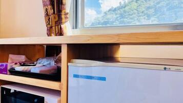Una habitación con ventana, microondas y refrigerador.