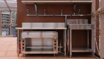 A commercial kitchen with stainless steel appliances, a fire extinguisher, and a metal shelf unit.