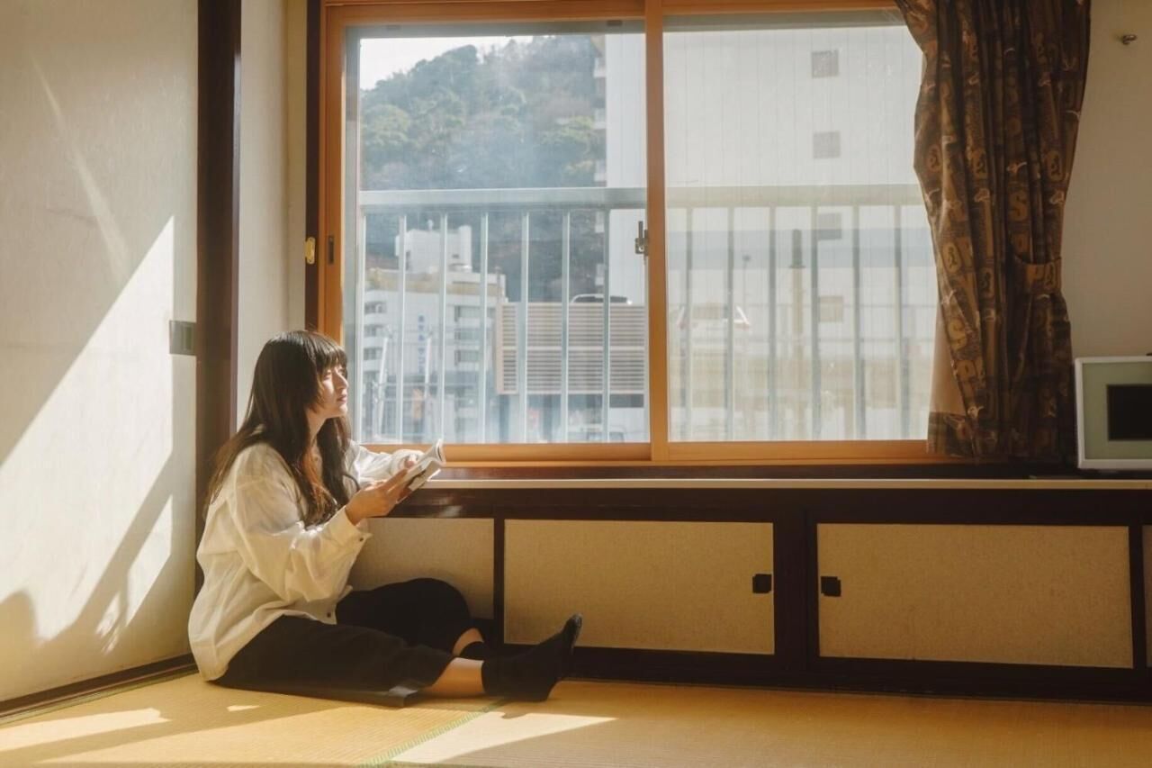 A person sitting by a window with a view of buildings outside.
