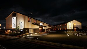 A hotel with a parking lot, marked parking spaces, and a building facade with signage. - Hotel Kan-raku Honjo Waseda Ekimae (Honjo)