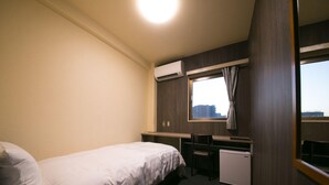 Ein Hotelzimmer mit Bett, Schreibtisch, Stuhl, Klimaanlage und einem Fenster mit Aussicht.