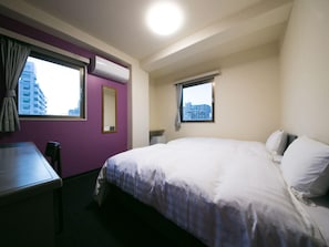 A hotel room with a bed, a desk, a chair, a window, and an air conditioning unit. - Hotel 910 (Oita)