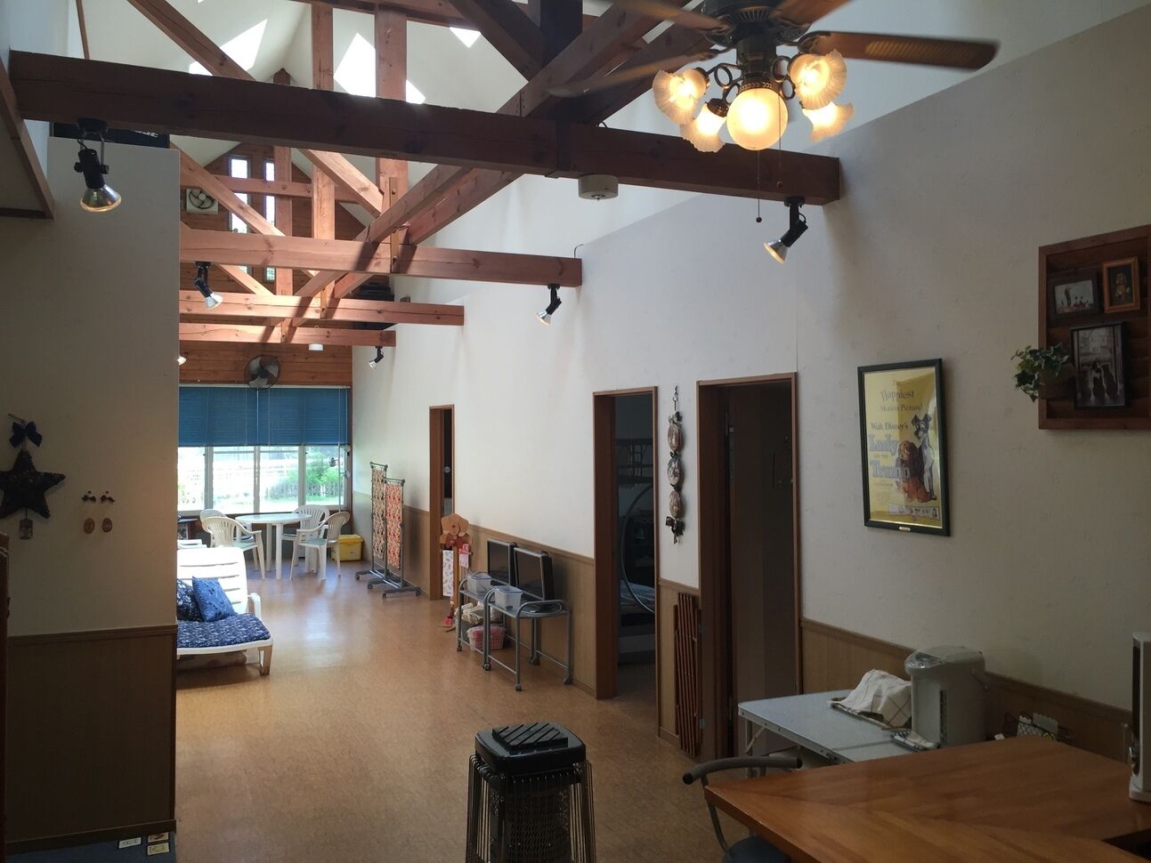 A spacious room with wooden beams, a ceiling fan, and a dining area with chairs and a table.