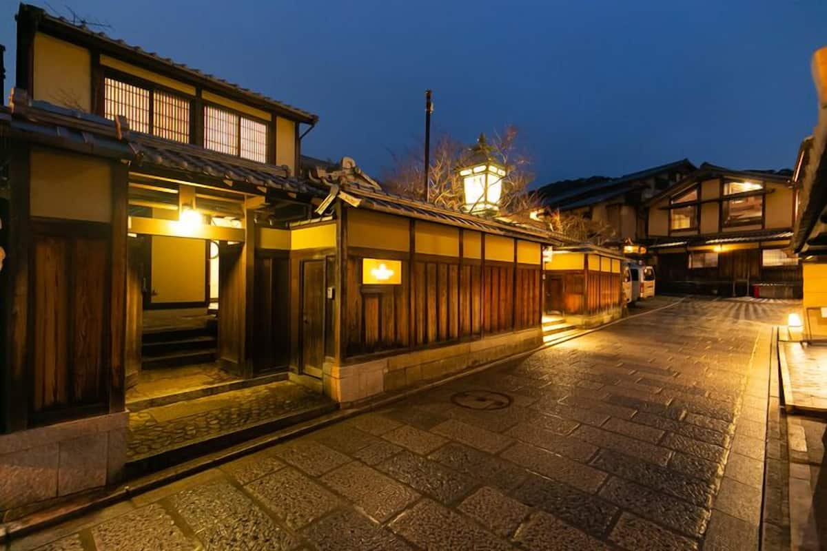 A traditional Japanese street at dusk with wooden buildings and a stone-paved road.