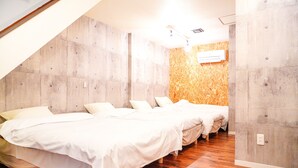 A bedroom with a sloped ceiling, wooden flooring, and a bed with white bedding. - ONE Hostel Himeji (Himeji)
