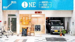 A hostel with a blue sign, a bar, and a car parked in front. - ONE Hostel Himeji (Himeji)