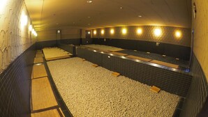 Ein Wellnessbereich mit mehreren Whirlpools, gefüllt mit Kieselsteinen, gefliesten Wänden und Wandleuchten.