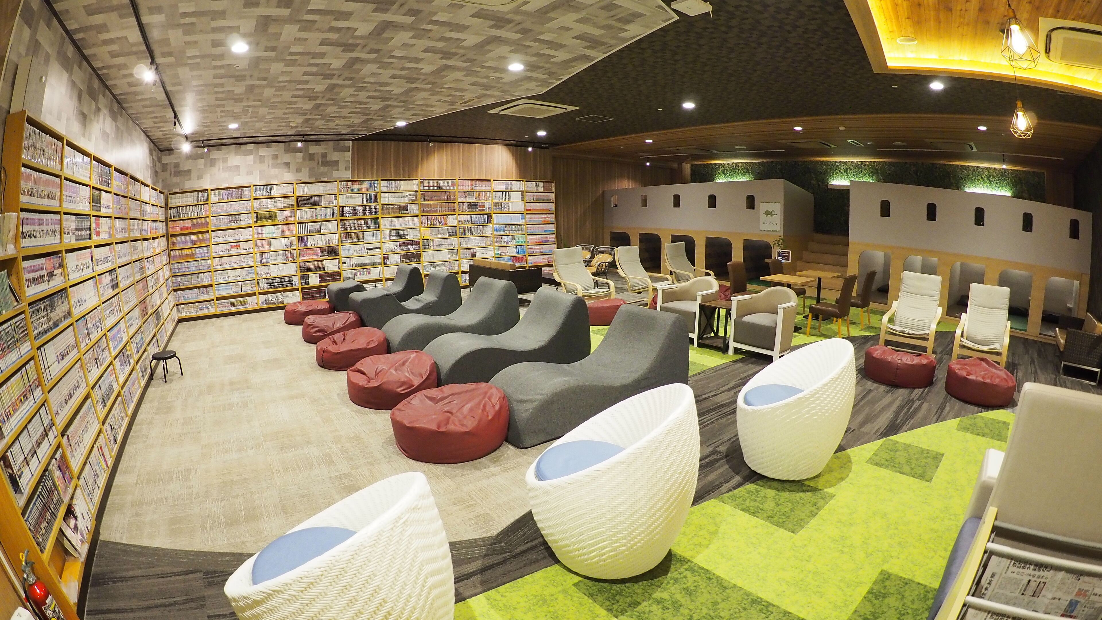 A library with bookshelves, seating areas, and a curved wall with windows.