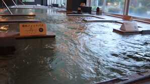 Ein Hallenbad mit klarem Wasser, Holzboden und Hinweisschildern in einer fremden Sprache.
