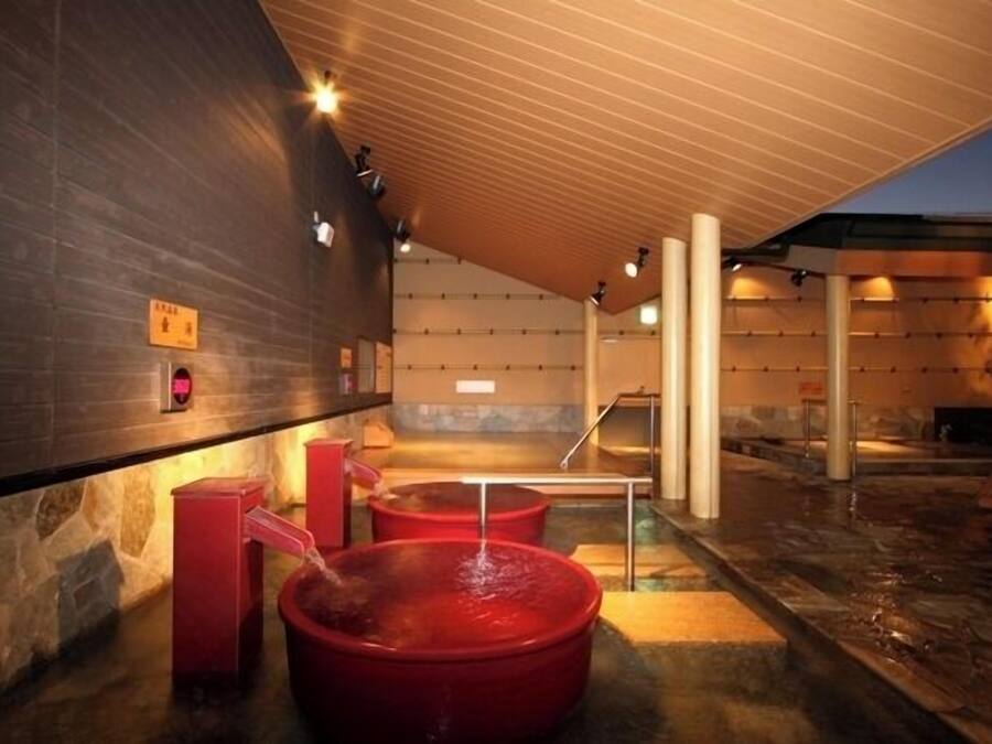A spa area with two red tubs, a stone wall, and a wooden ceiling.