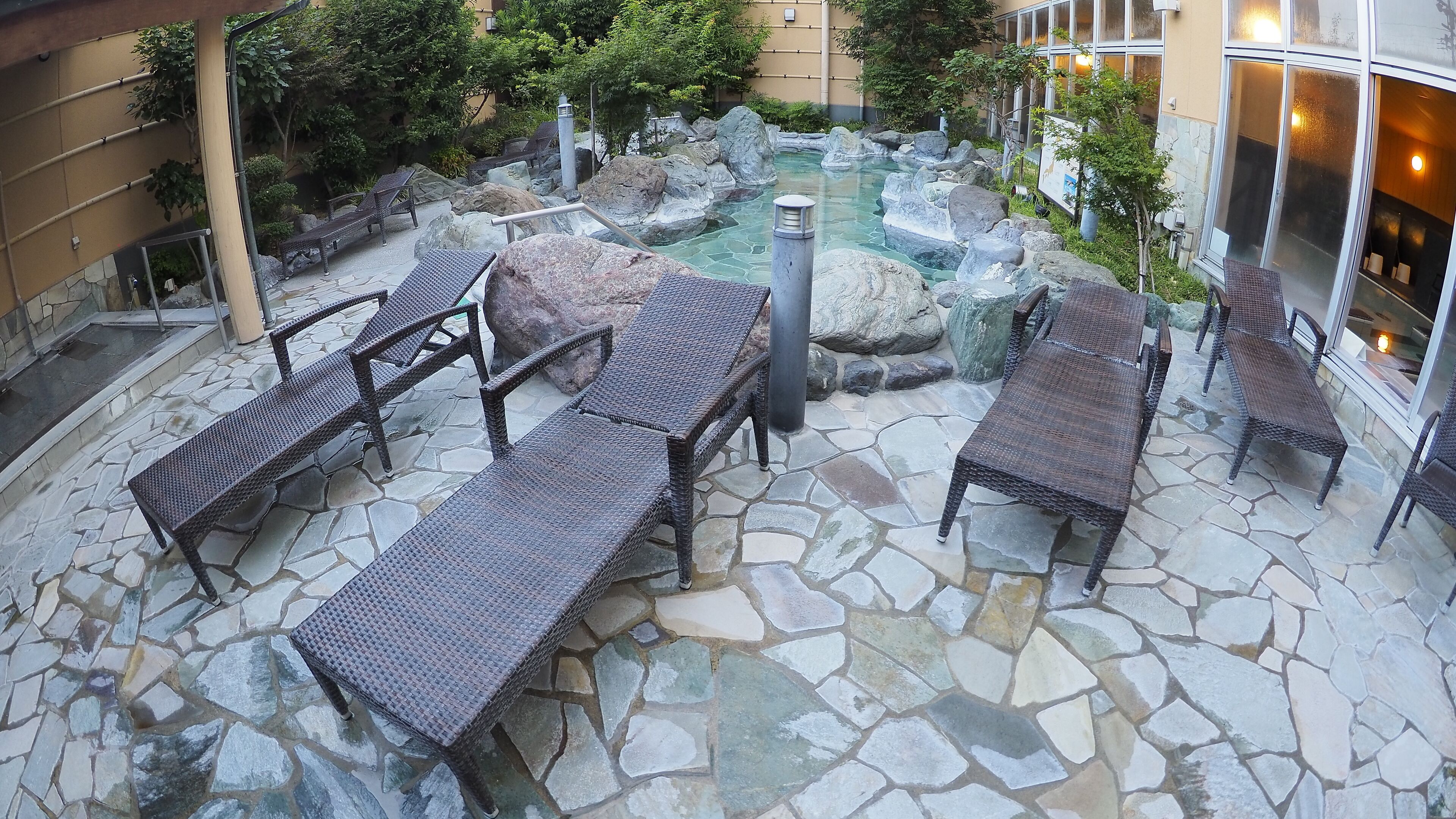 A stone-floored outdoor area with wicker furniture and a small rock garden.
