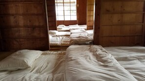 Une pièce aux murs en bois et un lit recouvert de draps blancs.