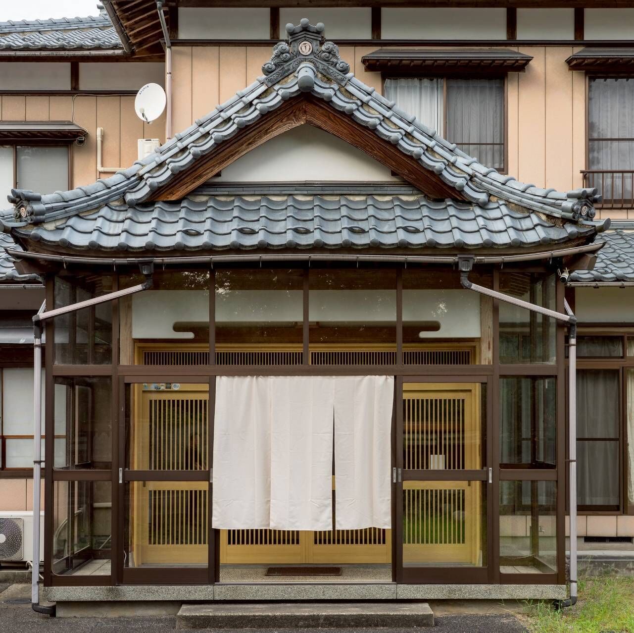 A traditional Japanese building with a tiled roof, sliding doors, and a small porch area.
