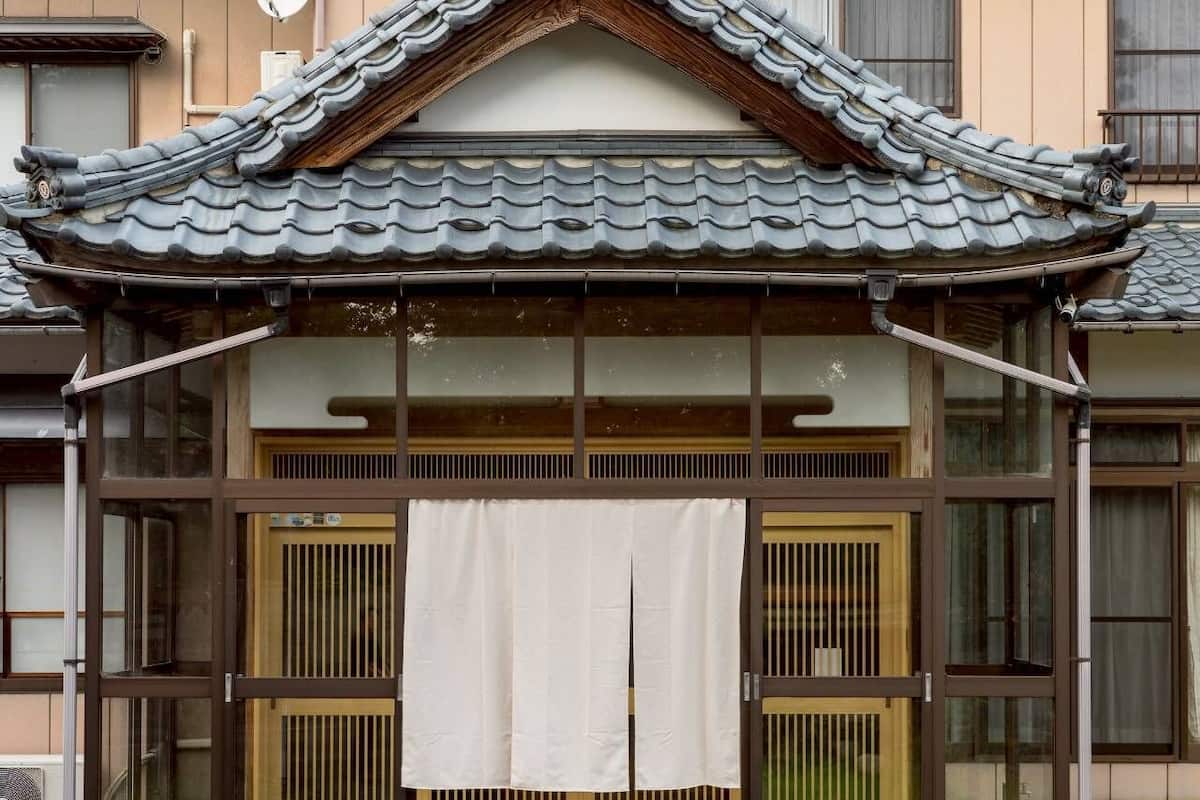 A traditional Japanese building with a tiled roof, sliding doors, and a small porch area.