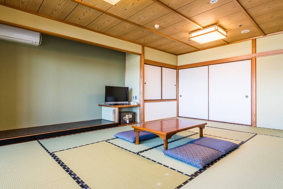 Una habitación con esteras de tatami, un televisor, un mueble pequeño y un calentador.