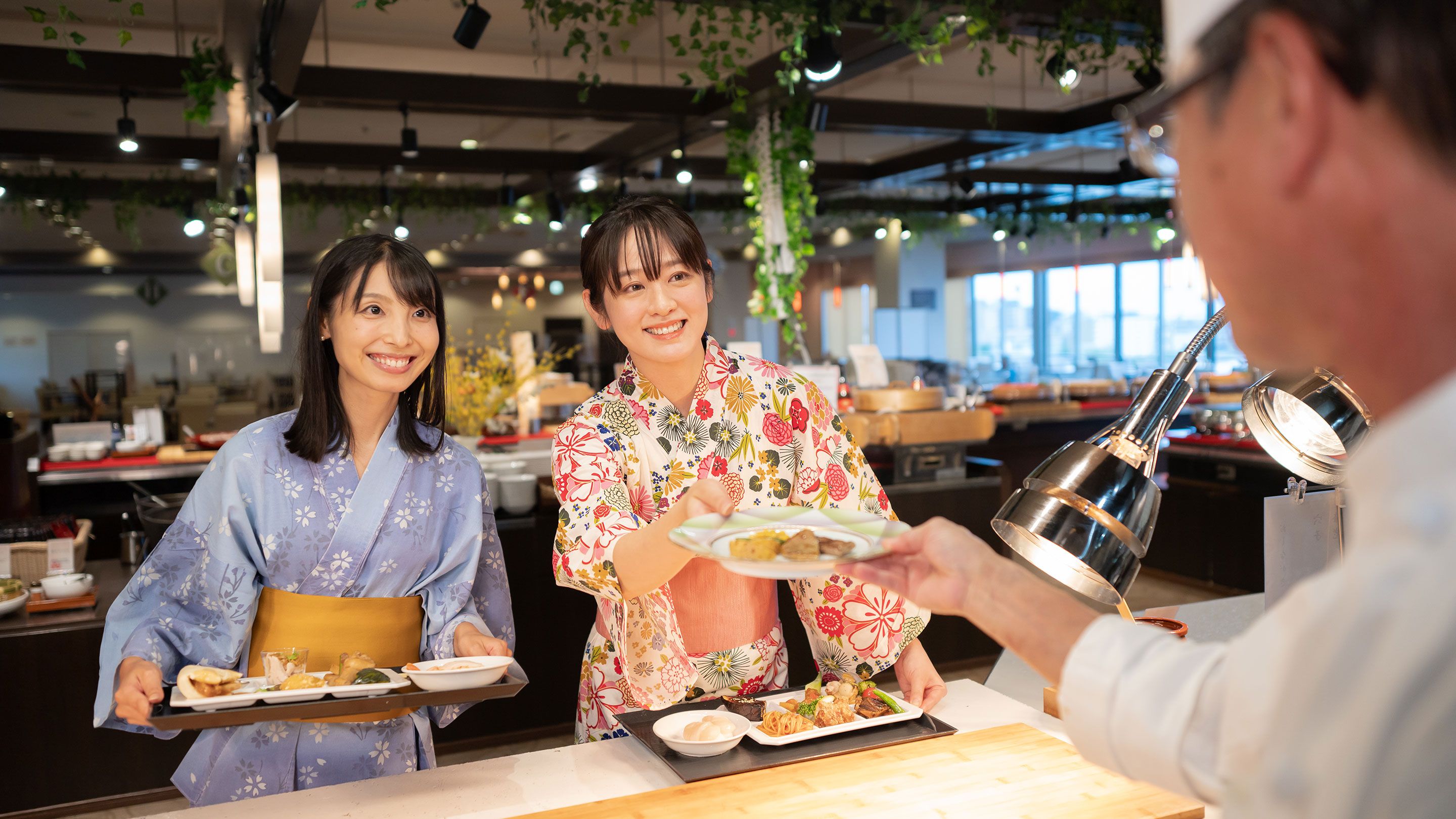 A restaurant interior with a counter, tables, and hanging plants.