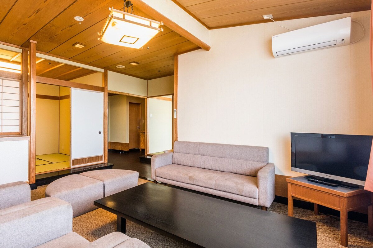 Een woonkamer met een bank, een salontafel, een televisie en een traditionele Japanse schuifdeur.