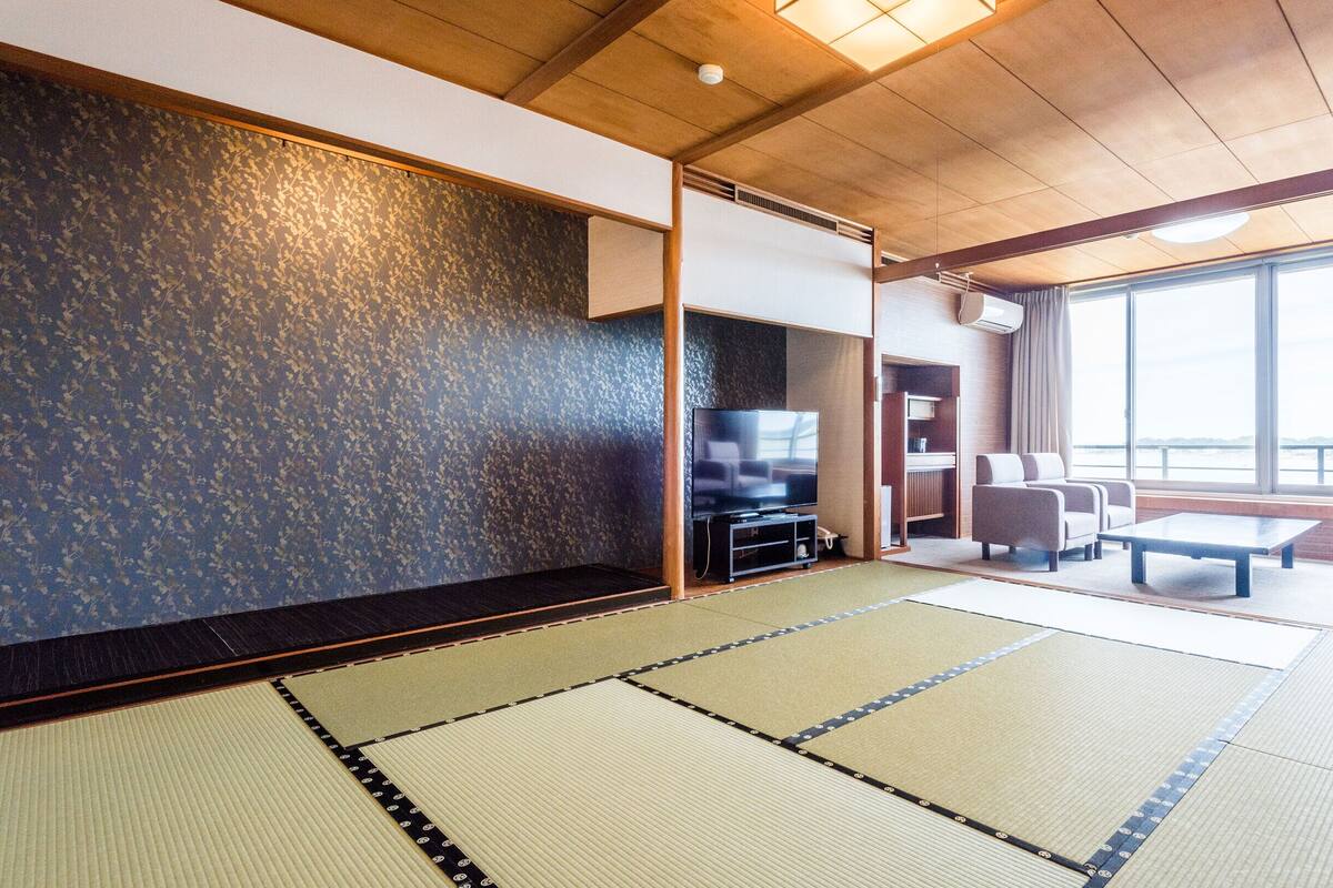 Una sala de estar moderna con esteras de tatami, un televisor de pantalla plana y un sofá.
