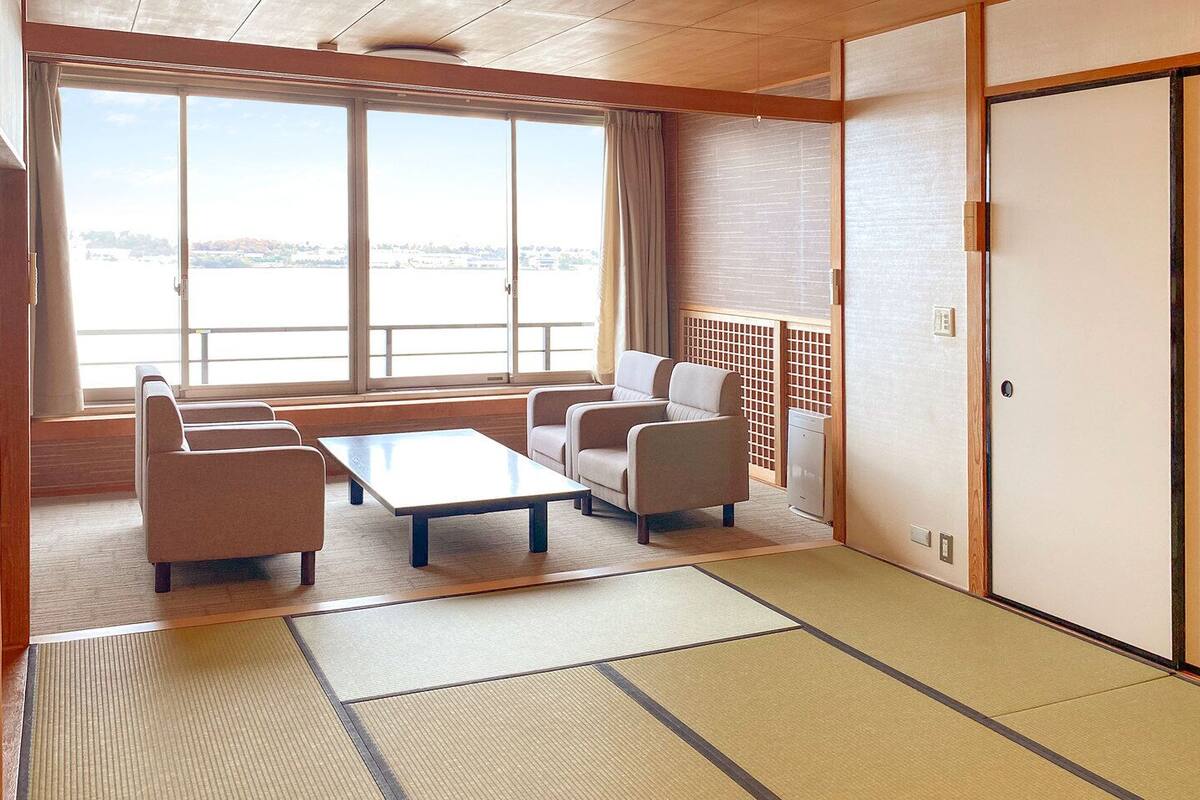 Ein traditioneller japanischer Raum mit Tatami-Böden, einem niedrigen Tisch und Sitzgelegenheiten.