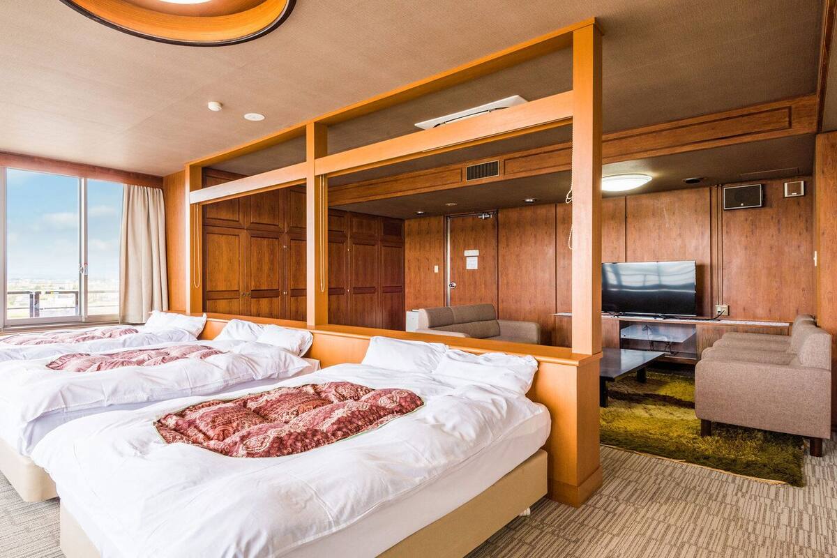 Ein Hotelzimmer mit zwei Betten, einem Fernseher und Blick zum Himmel.