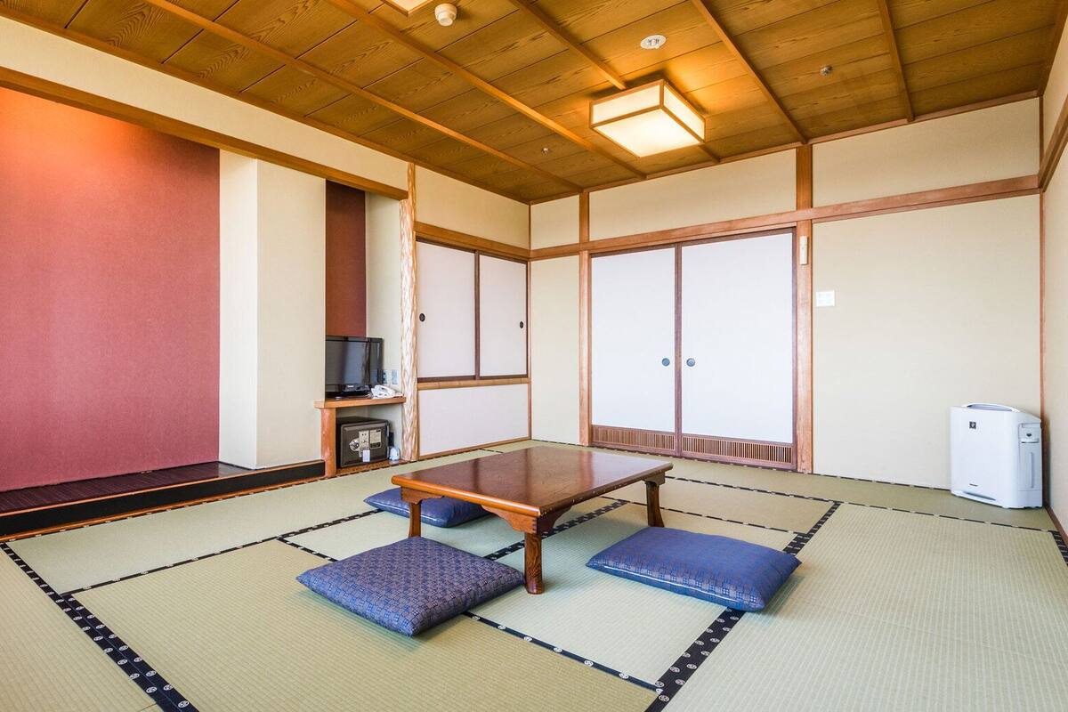 Ein traditioneller japanischer Raum mit Tatami-Bodenbelag, einem niedrigen Holztisch und Schiebetüren.